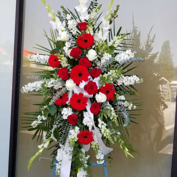 Large standing floral spray with red and white flowers on an easel
