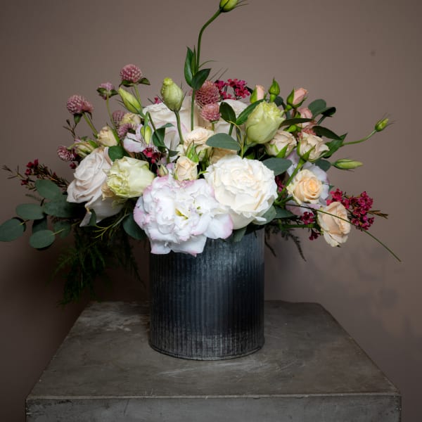Mixed bouquet of white and blush flowers in a dark metal vase