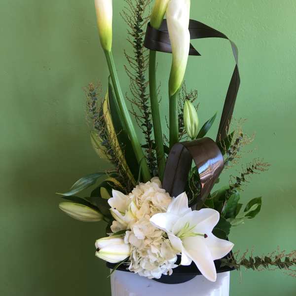 White calla lilies and lilies arranged with hydrangea in a vase