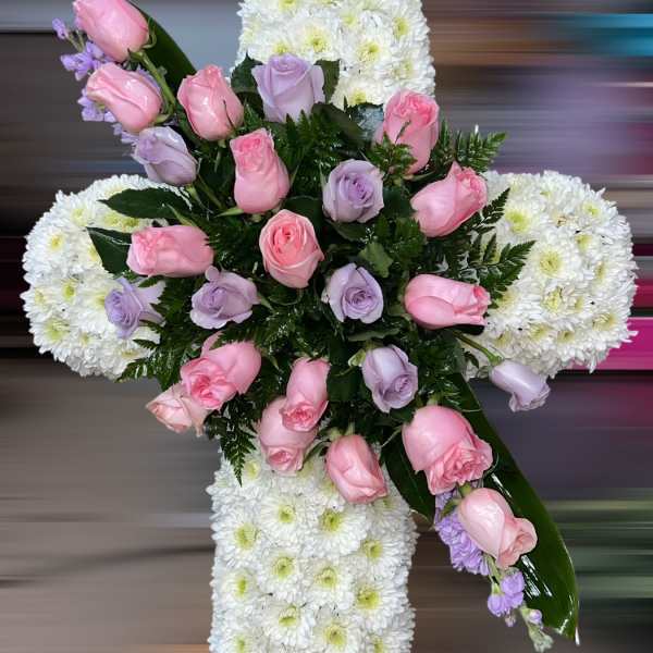 Tall white chrysanthemum cross with pink and lavender roses arranged in the center