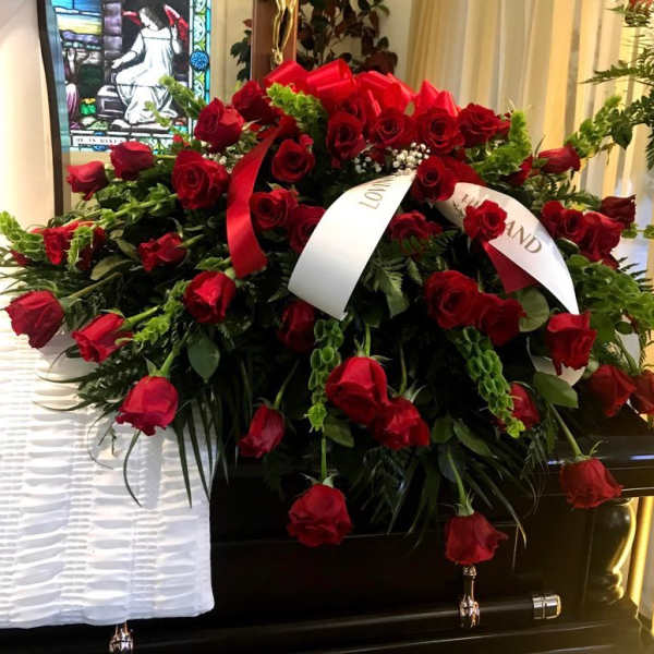 Large casket spray of red roses with white ribbons