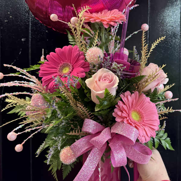 Pink gerbera daisies and roses with a Barbie balloon in a pink vase