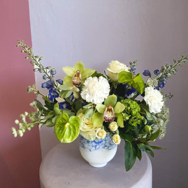 Mixed bouquet in a white vase with pale green orchids and white blooms