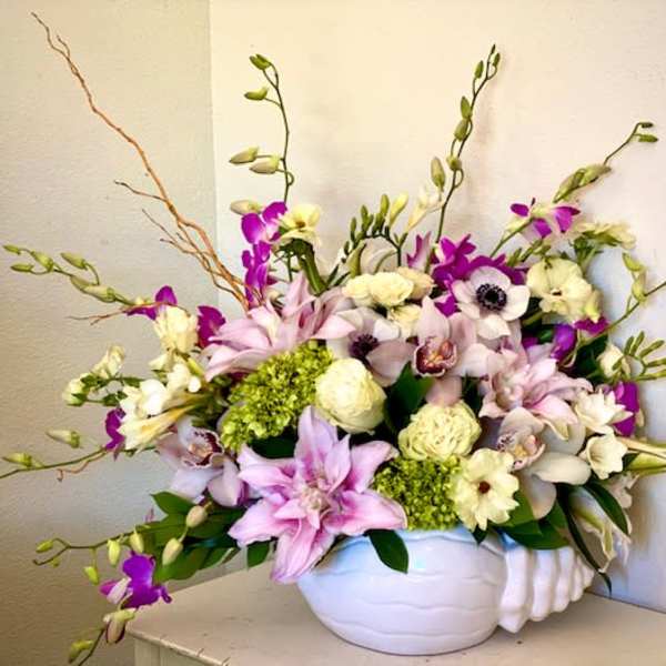 Mixed pink, white, and purple flowers in a white vase