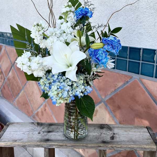 White lilies and blue carnations in a glass vase