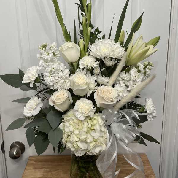 White floral arrangement in a glass vase with ribbon