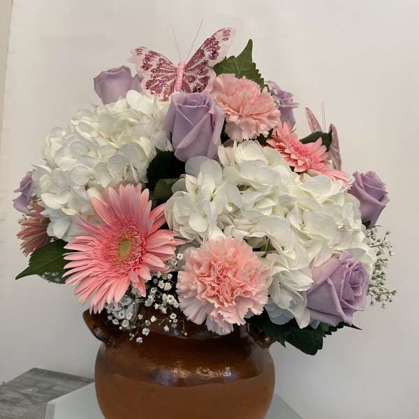 Pink and lavender bouquet with hydrangeas, roses, and gerbera daisies in a brown vase