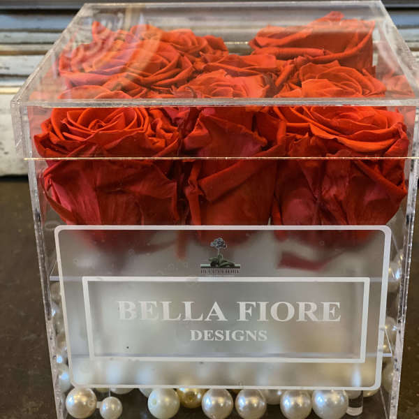 Red roses in a clear acrylic box with pearl accents