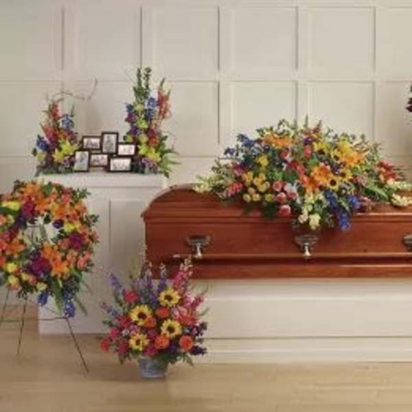 Sympathy set of colorful funeral sprays and wreaths surrounding a wooden casket