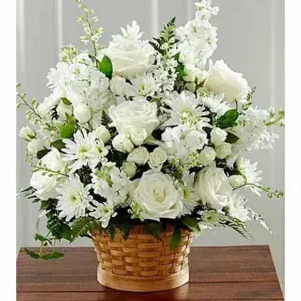 White roses and daisies arranged in a basket on a wooden table