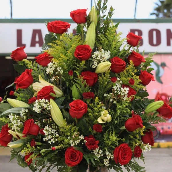 Tall arrangement of red roses and lilies in a glass vase