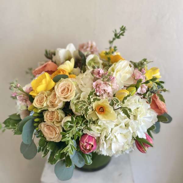 Mixed bouquet of pastel roses, tulips, and white blooms in a vase