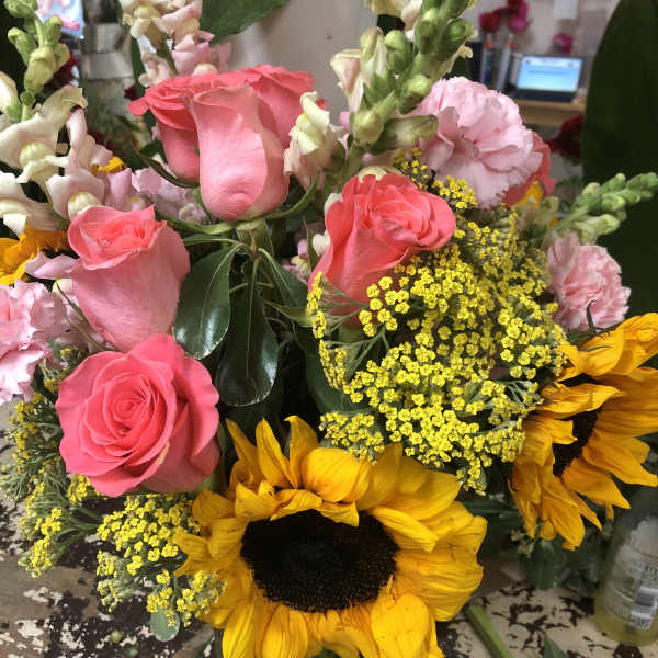 Bouquet of pink roses and yellow sunflowers in a glass vase