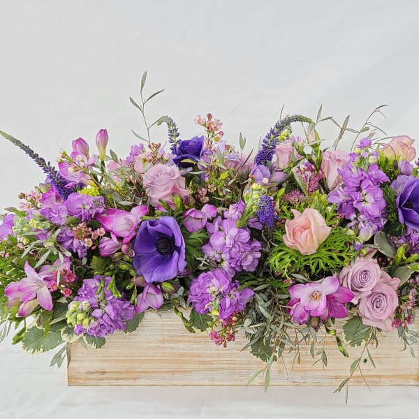 Purple and pink floral arrangement in a wooden box