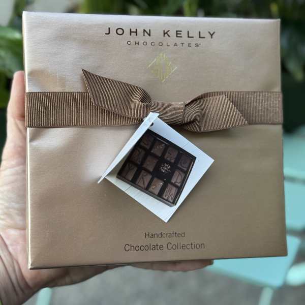 Box of assorted chocolates with a brown ribbon and gift tag