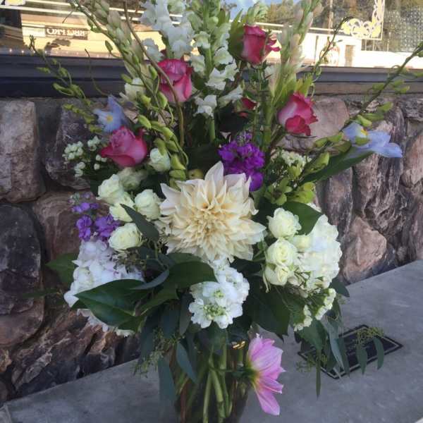 Tall mixed flower arrangement in a glass vase with pink, white, and purple blooms