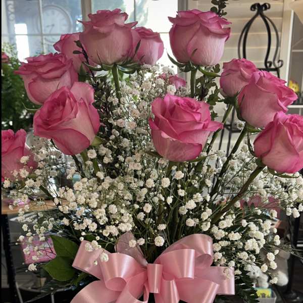 Pink roses with baby's breath in a glass vase and pink ribbon