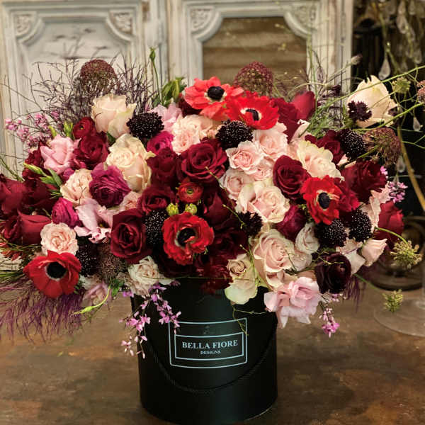 Large bouquet of red, pink, and cream roses in a black hatbox