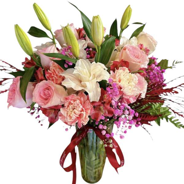 Pink and white mixed bouquet in a glass vase with a red ribbon