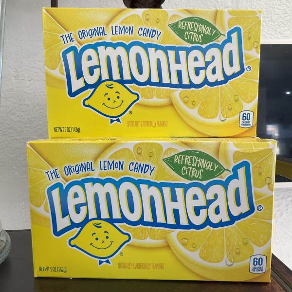 Two boxes of Lemonhead lemon candy stacked on a counter.