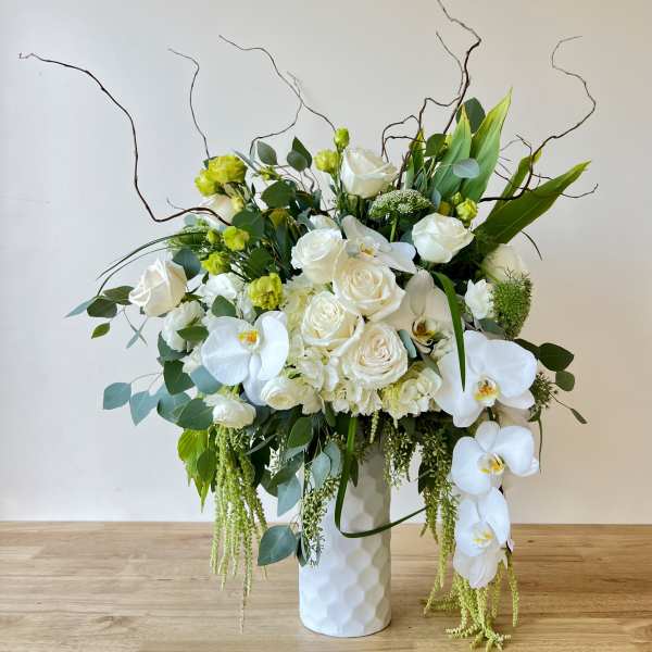 White roses and orchids in a tall white vase
