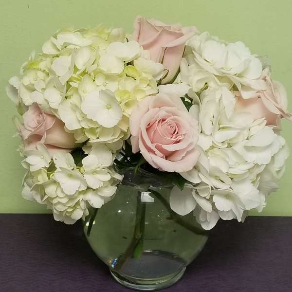 Pink roses and white hydrangeas in a clear glass vase