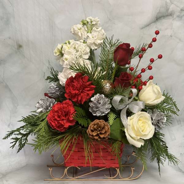 Holiday floral arrangement in a red basket with roses and carnations