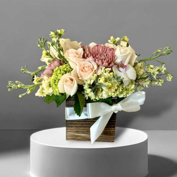 Bouquet of peach and cream roses with pink blooms in a wooden box