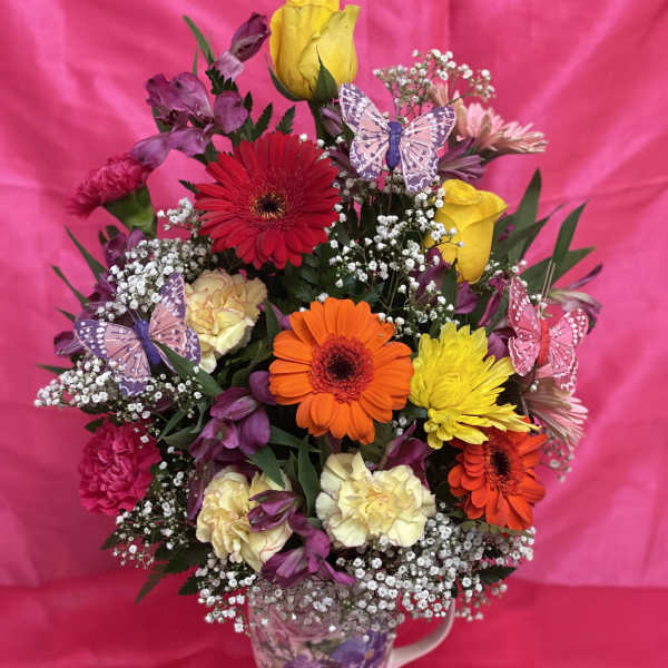 Colorful mixed flower bouquet in a floral mug with butterfly picks