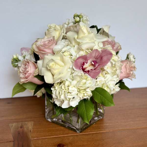 Pink and white roses with hydrangeas in a square glass vase