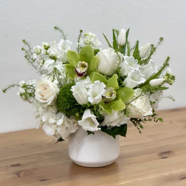 White floral arrangement in a white vase with green orchids and tulips