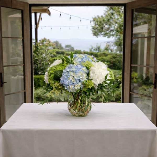 Blue and white hydrangea arrangement in a glass vase
