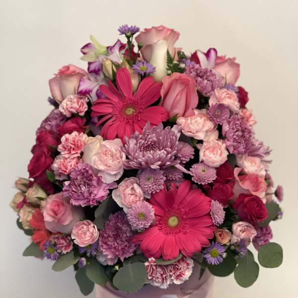Pink and purple mixed bouquet in a round pink box with a ribbon