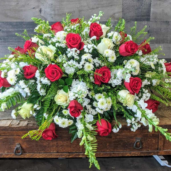 Large red and white rose and snapdragon spray arrangement on a wooden table