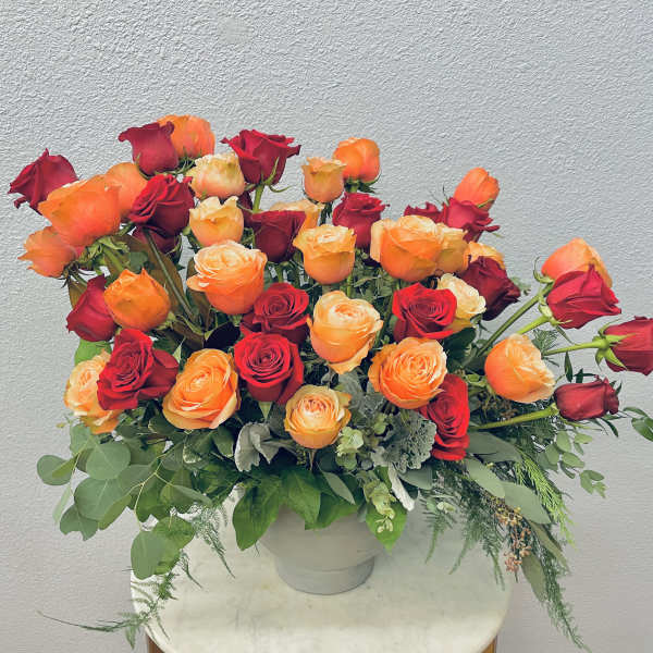 Bouquet of red and orange roses in a white vase