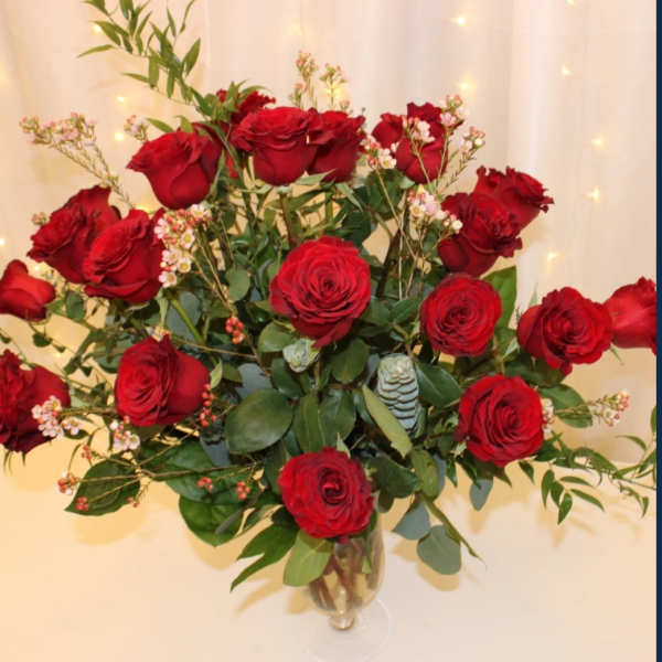 Red roses arranged in a clear glass vase with greenery