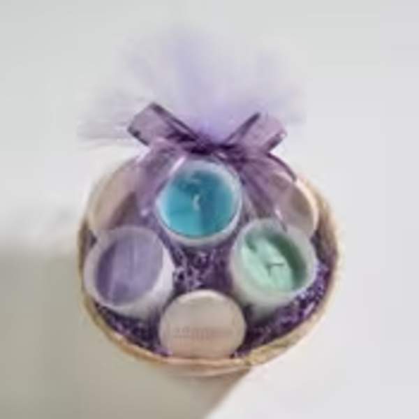 Small gift basket of assorted pastel candles wrapped in purple tulle with a bow