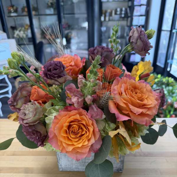 Orange and purple roses arranged in a square container