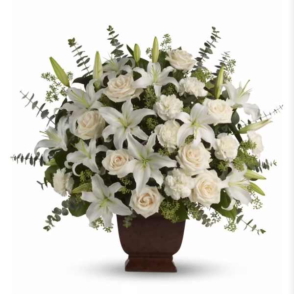 White lilies and roses arranged in a dark urn vase