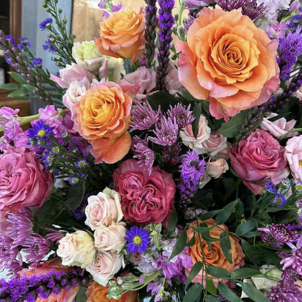 Bouquet of orange and pink roses with purple filler flowers