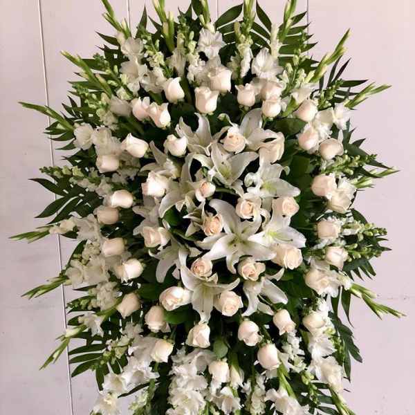 Large white funeral spray with roses and lilies on a stand