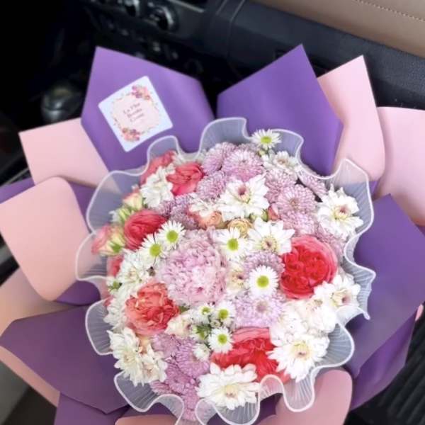 Bouquet of pink, white, and purple flowers wrapped in pastel paper