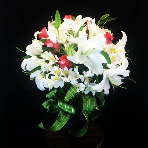 Bouquet of white lilies and red roses with a green ribbon bow