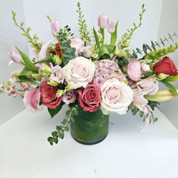 Mixed pink and white flowers arranged in a green glass vase