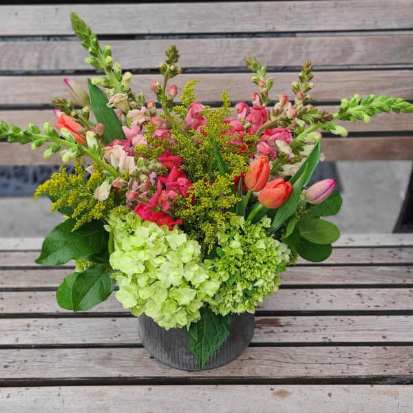 Mixed bouquet in a dark container with pink and green flowers