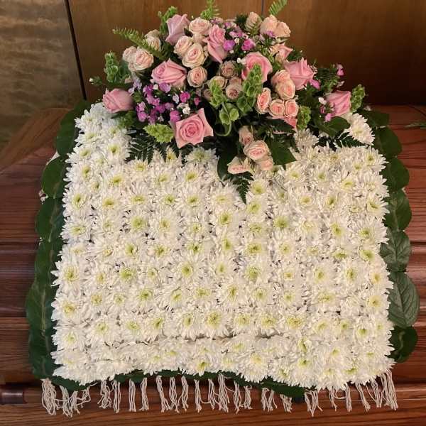 White chrysanthemum floral tribute with pink roses on top
