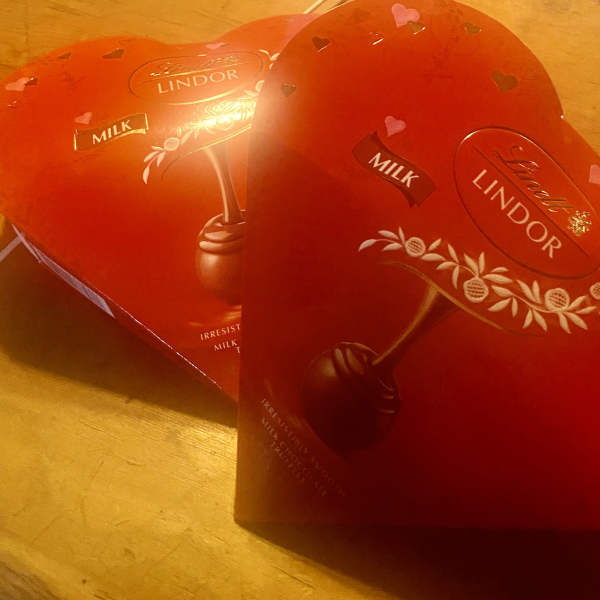 Two heart-shaped Lindor chocolate boxes on a wooden surface