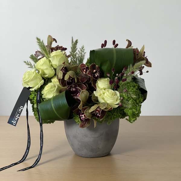 Green and burgundy floral arrangement in a gray vase