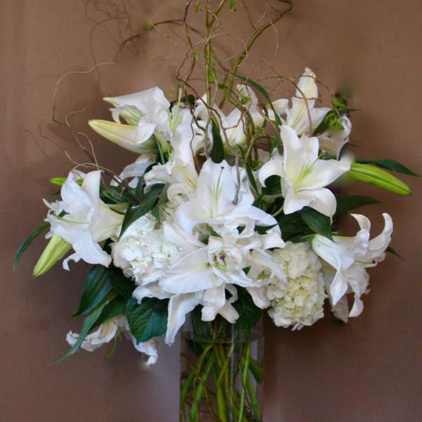 White lilies and hydrangeas in a tall glass vase