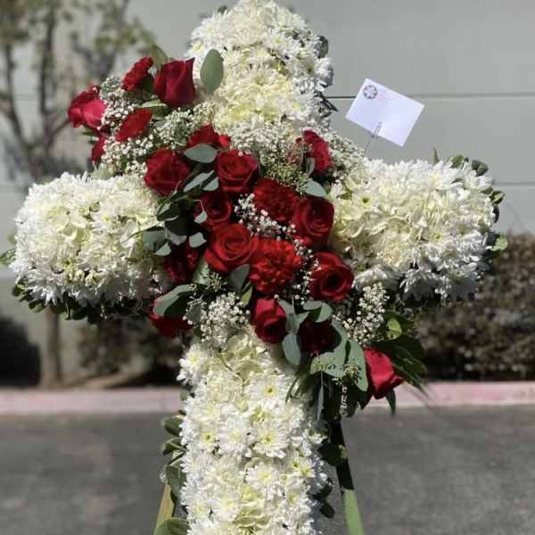 Cross-shaped floral tribute with red roses and white flowers